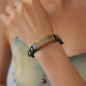 Close-up of leather bracelet with engraved bronze plate Love is the key to happiness
