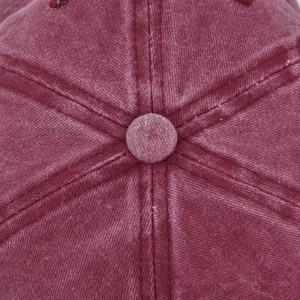 Macro shot of the top button and stitched seams on the maroon washed cotton baseball cap