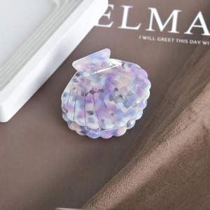 Macro shot of shell shaped acetate hair claw clip with colorful marble texture details