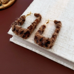Macro shot of rectangular leopard print plush earrings with gold plated metal needles