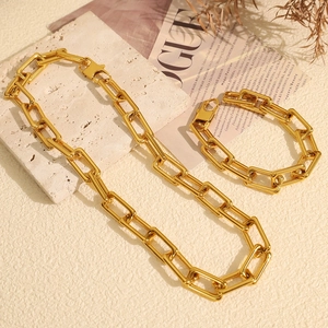 Chunky gold chain necklace and bracelet set in minimalist aesthetic on stone background