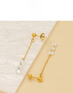Detail of gold-plated long tassel earrings with three clear crystals on ceramic plate