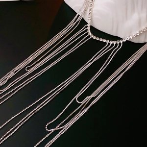 Détail de collier à glands argenté avec cristaux étincelants sur mannequin blanc