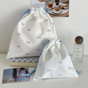 Set of two cream canvas drawstring bags with blue bow prints in small and large sizes