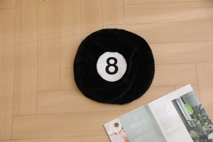 Detail of a black 8-ball plush rug with soft shaggy texture on a light wood floor
