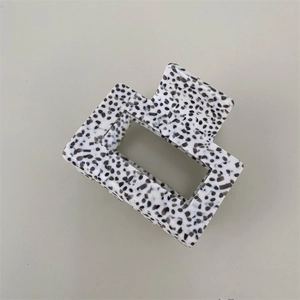 Close-up of square acetate hair claw clip featuring a black and white spotted marble texture