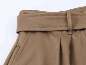 Close-up of khaki midi skirt waist with twill texture, belt loops, and pleated details