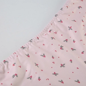 Détail du tissu floral rose avec motif de baies et finition de couture soignée
