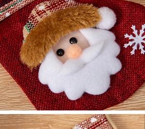 Close-up of burlap Christmas stocking featuring Santa Claus plush and snowflake embroidery