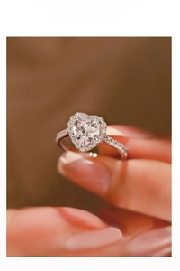 Macro shot of S925 silver heart shaped moissanite ring with halo setting on finger