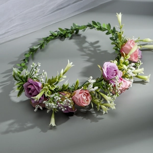 Close-up of pink and purple silk roses with green leaves on a floral bridal headband