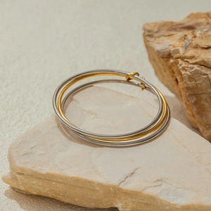 Detail of interlocking silver and 18K gold stainless steel triple-layered band bracelet