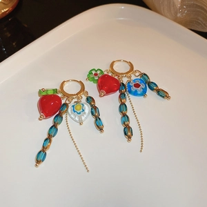 Détail de boucles d'oreilles en cristal avec cœurs rouges et fleurs bleues sur anneaux