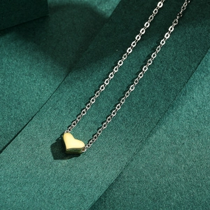 Minimalist S925 silver necklace with golden heart pendant on deep green background