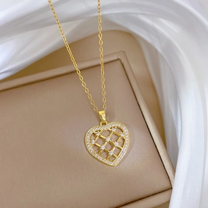Détail du pendentif cœur doré avec zircons sur un écrin beige et tissu en soie