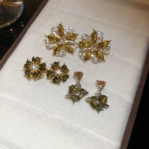 Close-up of emerald green flower earrings and heart pendant in a velvet jewelry box