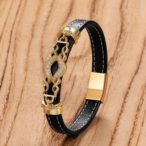 Détail d'un bracelet en cuir noir pour homme avec fermoir magnétique doré et cristaux