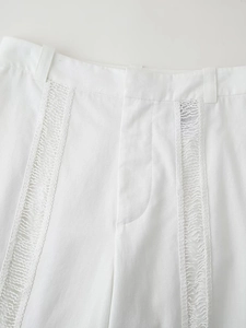 Gros plan détaillé d'un pantalon blanc en lin avec dentelle ajourée délicate à la taille