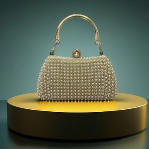Detail of luxury pearl evening bag featuring a gold metal handle and a large pearl clasp