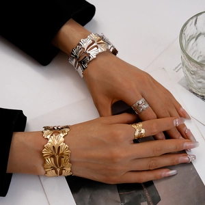 Gros plan de bracelets et bagues feuilles de ginkgo dorés et argentés sur un mannequin
