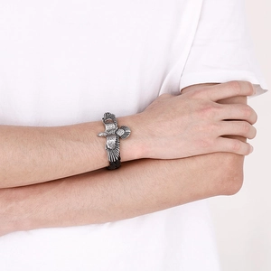 Detail of eagle charm punk bracelet with black woven leather cord on male wrist