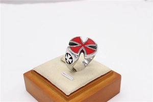 Detailed close-up of a men's stainless steel ring with a red Maltese cross on a wood stand