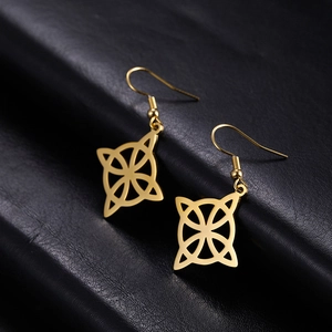 Close-up of golden stainless steel Celtic knot earrings on black leather texture