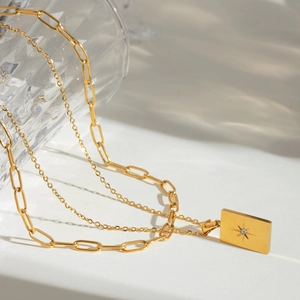 Detail of gold layered paperclip necklace with rectangular star pendant and zircon stone