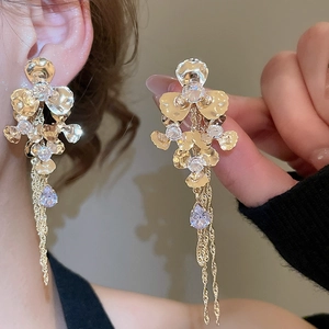 Macro detail of gold flower earrings with tassels and light purple crystal drops