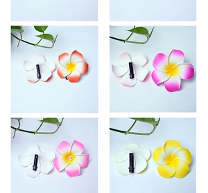 Detail of four colorful foam plumeria hair clips in gradient shades on blue background