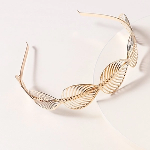 Elegant gold metal leaf headband with hollowed-out leaf design on minimalist background