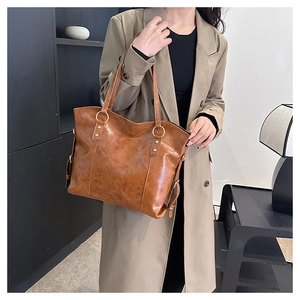 Detail of tan leather tote bag showing fine texture and sleek metallic ring strap connector