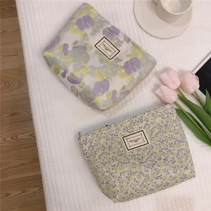 Detailed view of floral canvas makeup bags with 'TIME TO PARTY' patch and zip closure