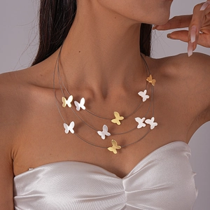 Close-up of triple-layered butterfly necklace with gold and matte white metallic pendants