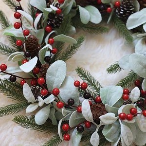Christmas wreath with red berries, pine needles, and eucalyptus leaves on white rug