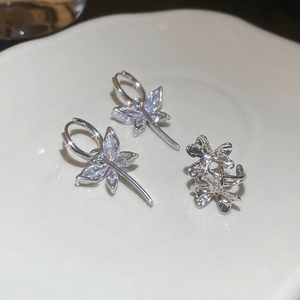 Macro shot of silver butterfly tassel earrings with zircon stones on a white ceramic plate
