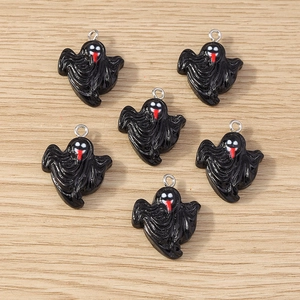 Detail of glossy black resin ghost charms with silver metal rings on wooden surface