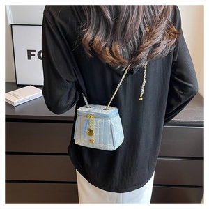 Detail of light blue tweed mini bucket bag with gold chain and camellia charm decoration