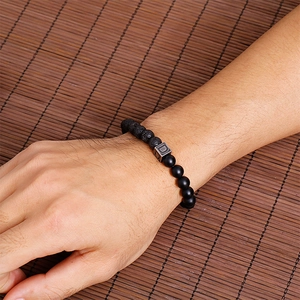 Men's lava stone beaded bracelet with letter D charm on a brown woven background