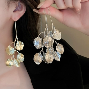 Close-up of golden leaf earrings with detailed veins worn by a fashion model