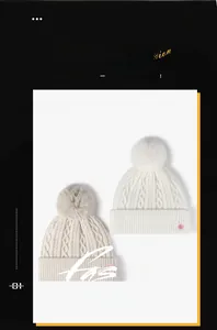Detail of cable knit beanies with faux fur pom-poms and cherry embroidery accents
