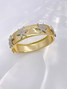 Adjustable golden cuff bracelet featuring silver star charms with white cubic zirconia