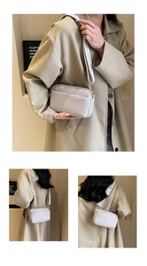 Close-up of light gray PU crossbody bag with beige V-patterned wide shoulder strap