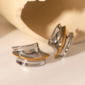 Detail of chunky wavy earrings in polished silver and gold two-tone stainless steel