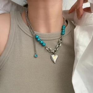 Close-up of a double-layered necklace featuring a blue bead and heart pendant