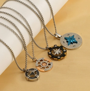 Detailed view of four vintage compass pendants in silver, gold, black, and blue finishes