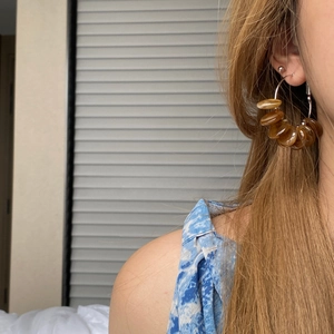 Close-up of retro brown translucent resin bead hoop earrings worn on a model's ear