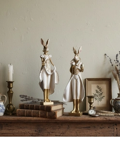 Detailed close-up of rabbit figurines in elegant formal dresses on vintage wooden surface