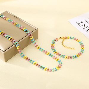 Detail of candy-colored enamel wheat necklace and bracelet set on a gold jewelry box