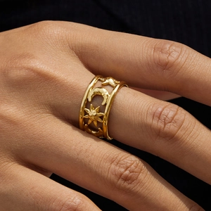 Detail of gold celestial ring with sun, moon, and star cutouts on hammered metal band